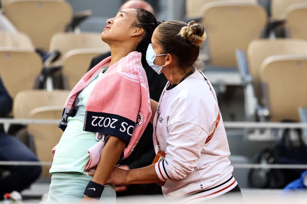 A woman massages the back of another woman in a tennis uniform.