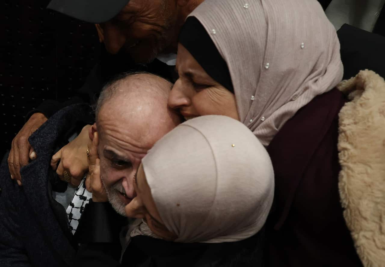 Two women embrace a man