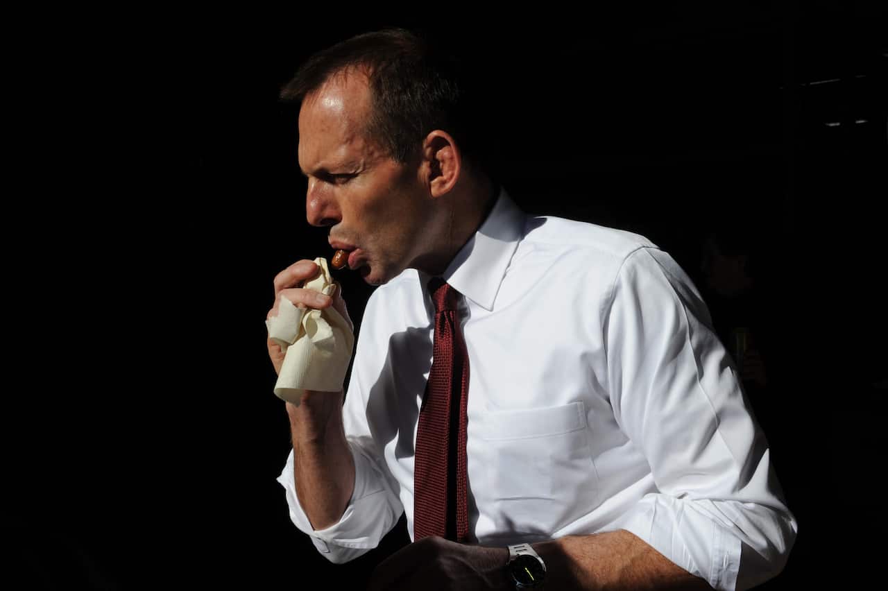 Man takes a bite of a sausage.