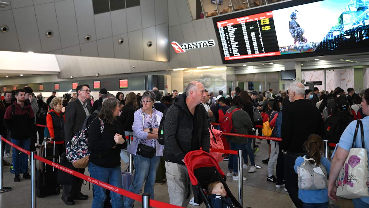 Crowd of people lined up in a airport.