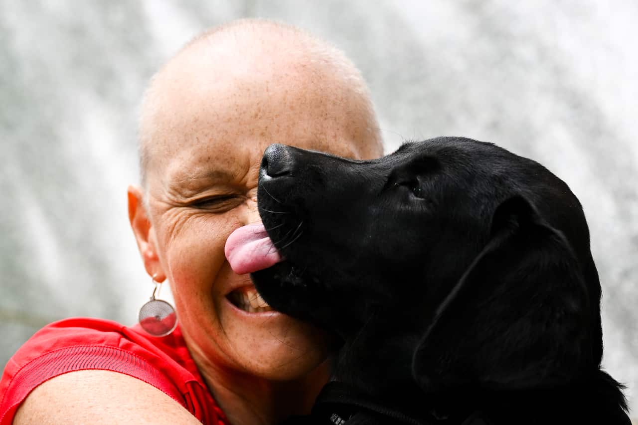 A woman smiling as a dog licks her face