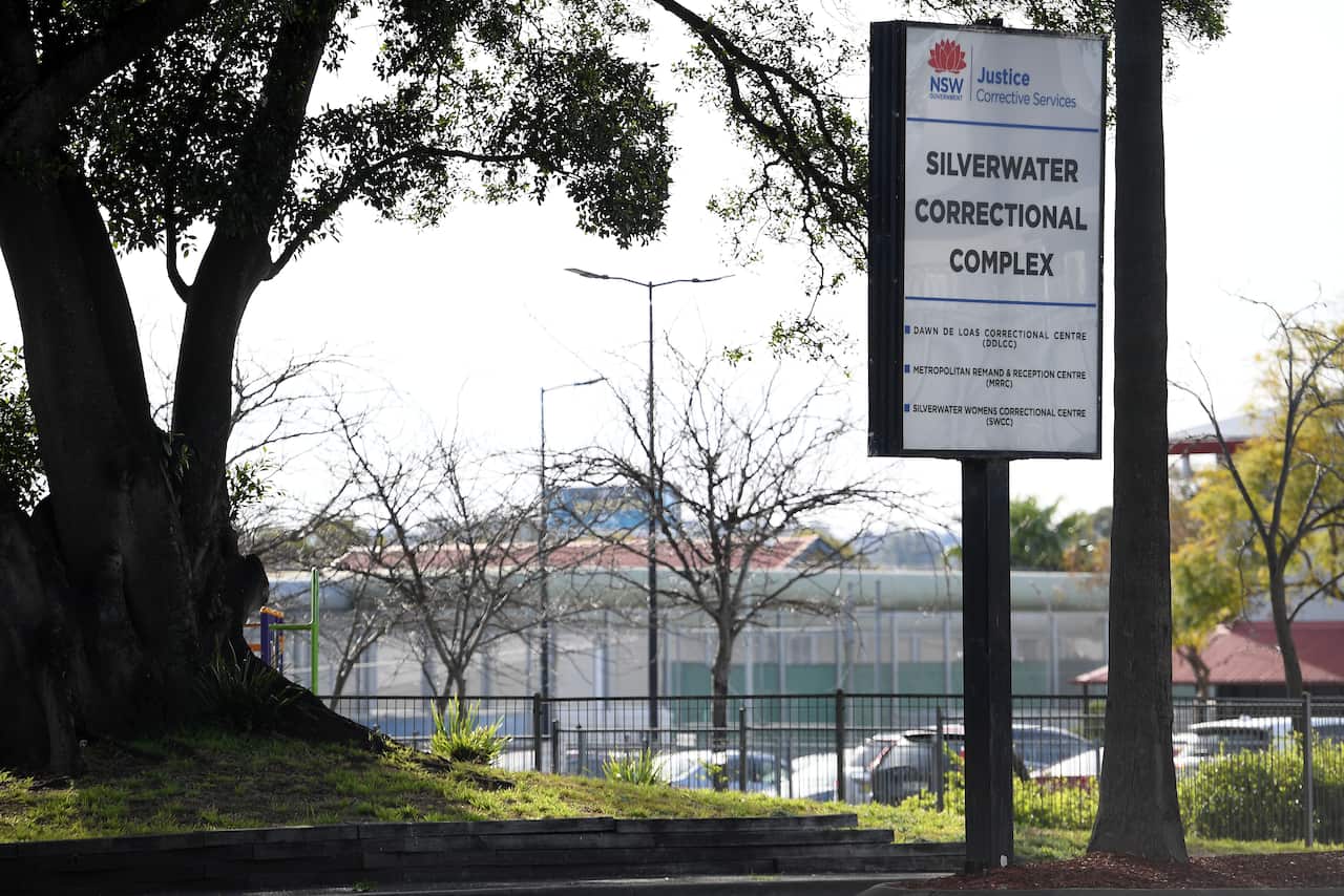 A large white sign outside a fence. Large black writing reads Silverwater Correctional Complex 