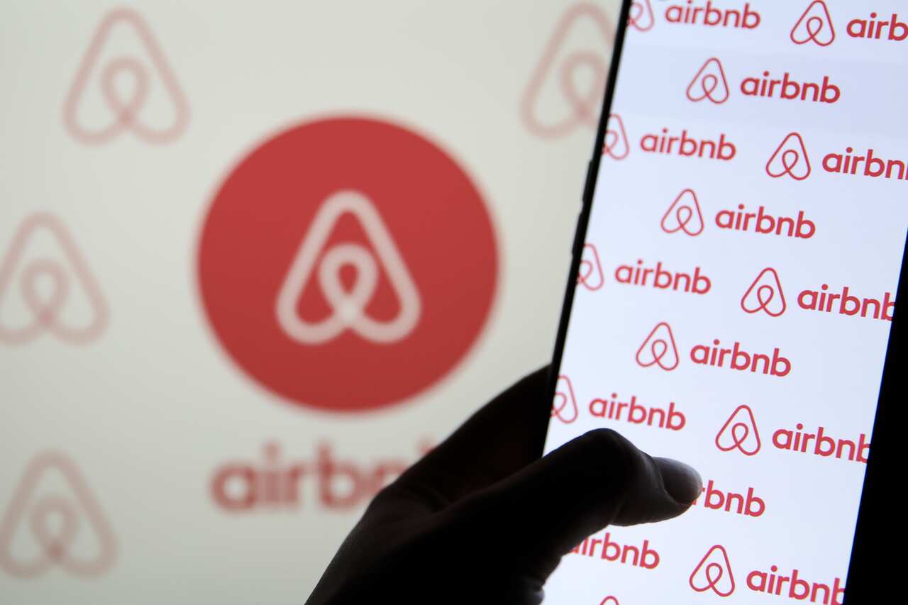The Airbnb logo is seen on a phone screen.