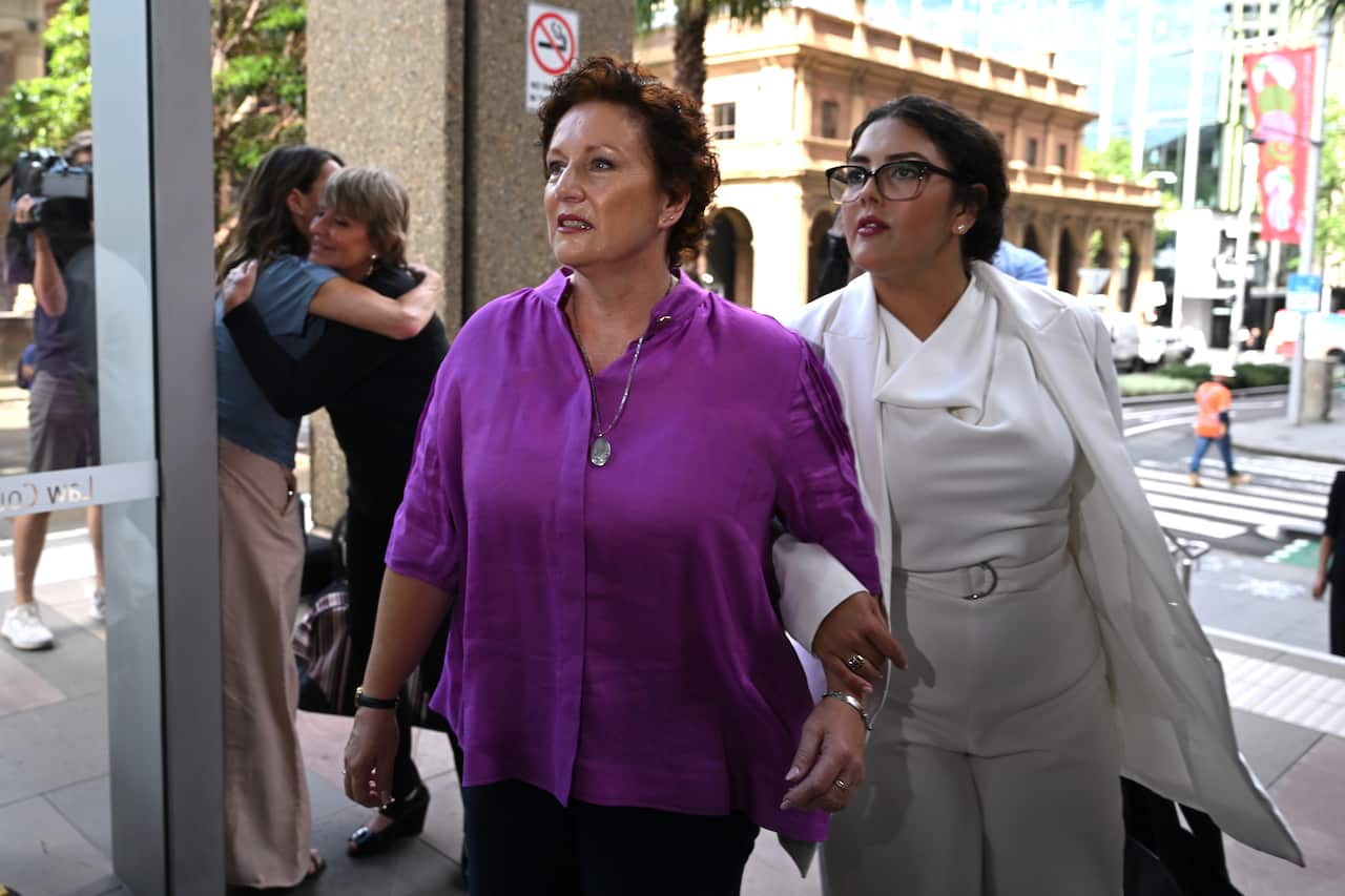 Two women with arms linked enter a building.