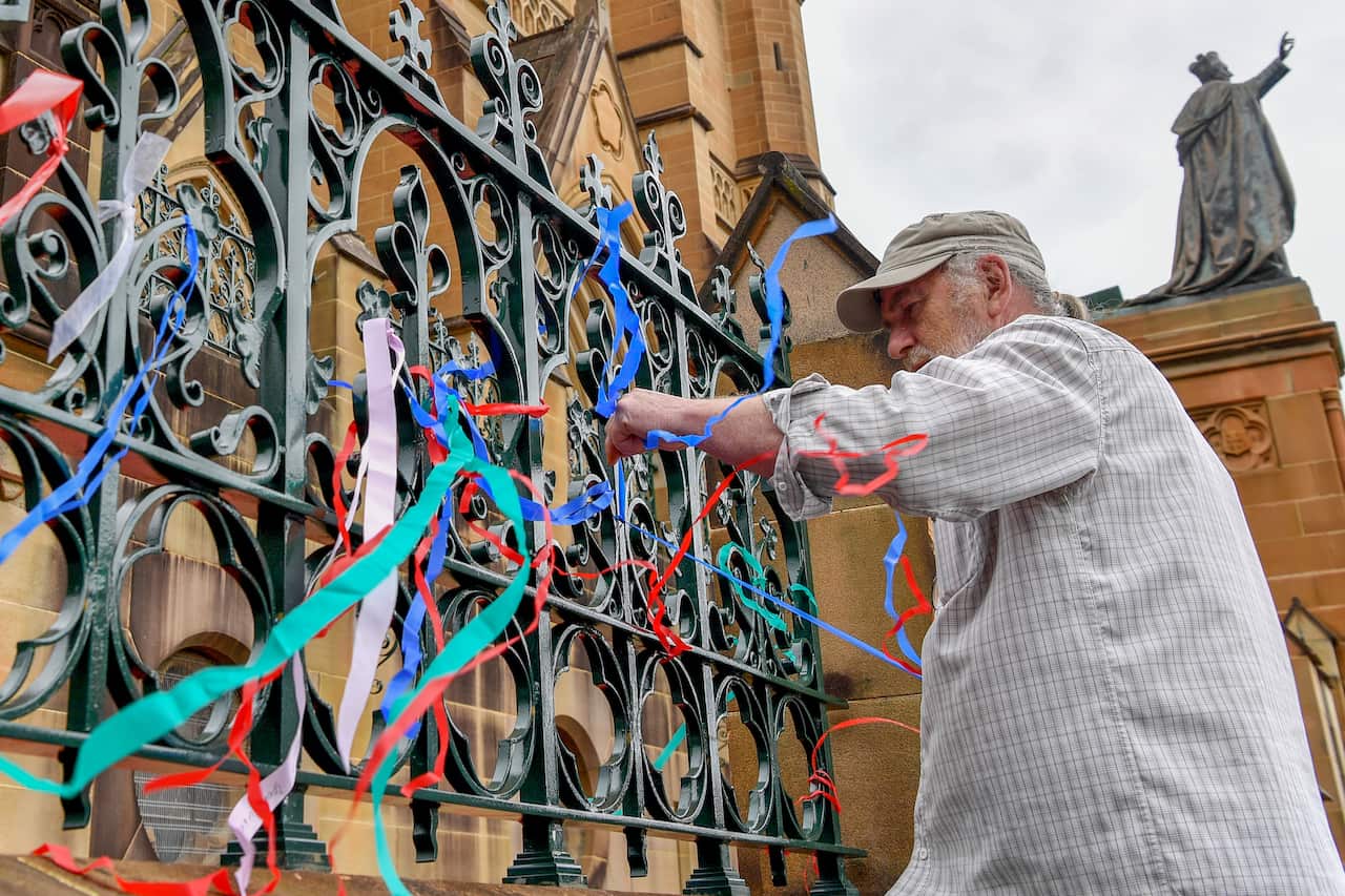 A man tying ribbons to a fence