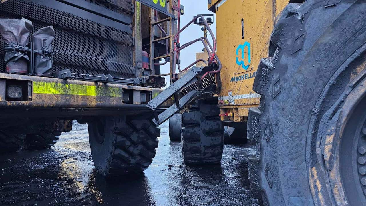 A photo of a mining haul truck colliding with a dozer on wet coal-covered soil.