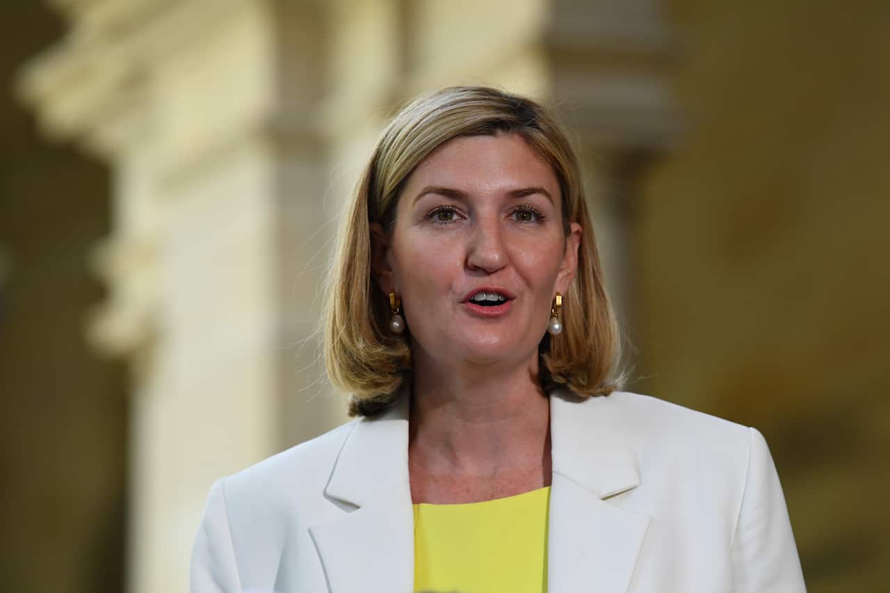 A woman in a yellow top and white jacket.