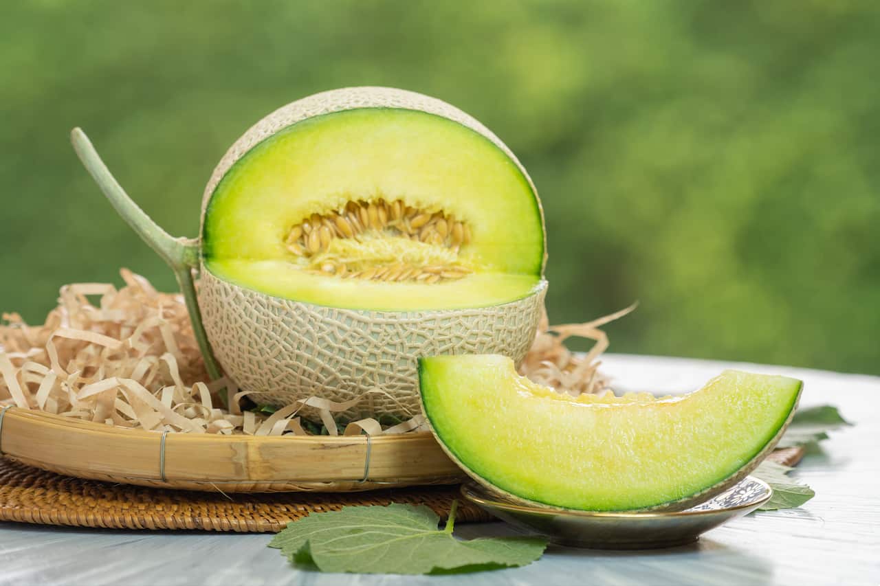A crown melon on a white table, on a plate.