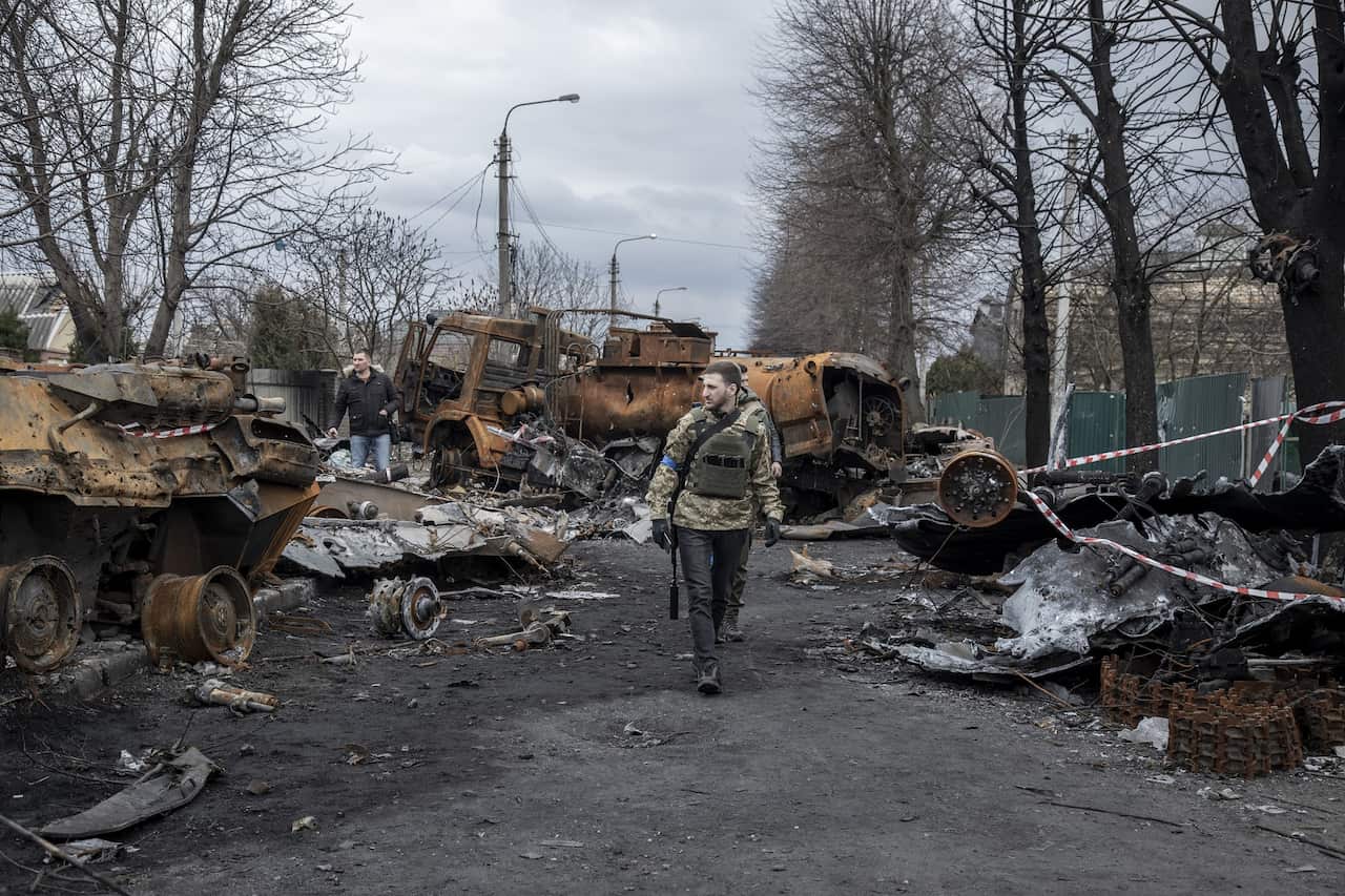 A man walking among burnt-out military vehicles