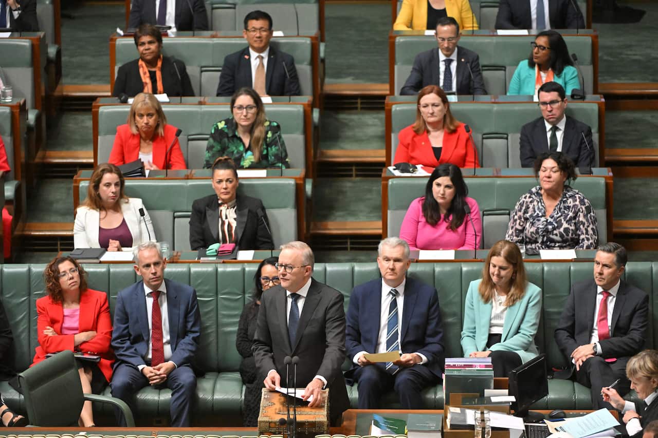 A man wearing a suit speaks at a lecturn. 
