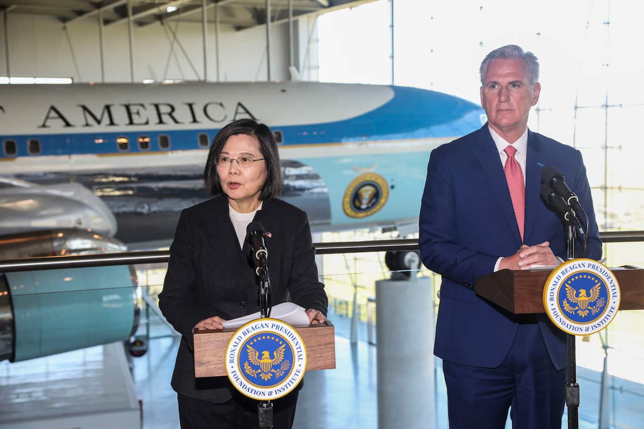 A man and a woman standing at lecterns in front of microphones.