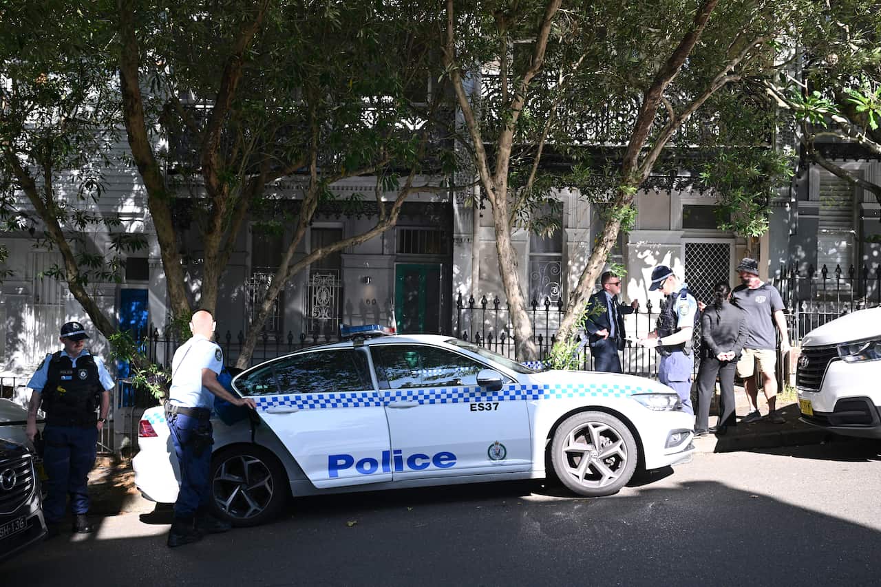 The police car and a few officers are in front of a small house.