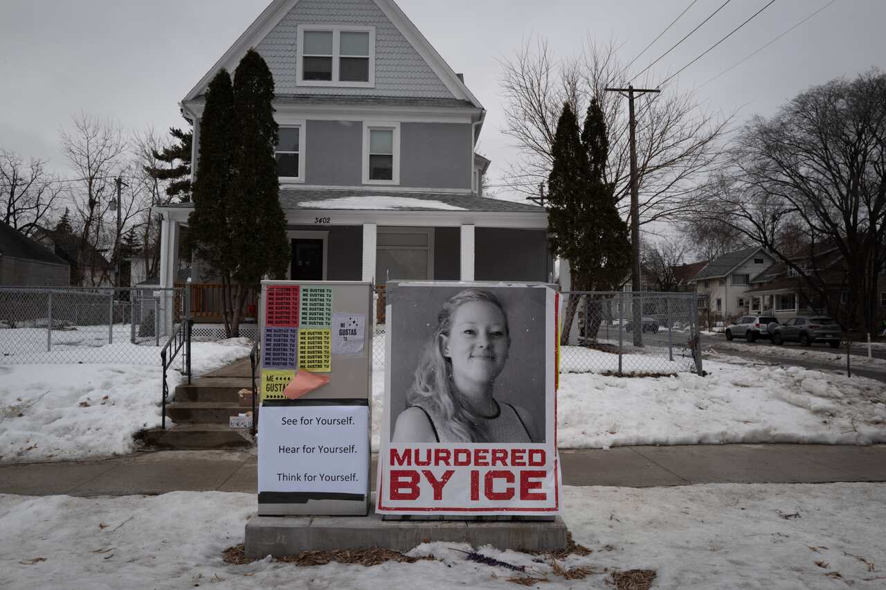 A black and white image of a white woman on a poster that reads 'murdered by ICE'. A house surrounded by snow is in the background. 