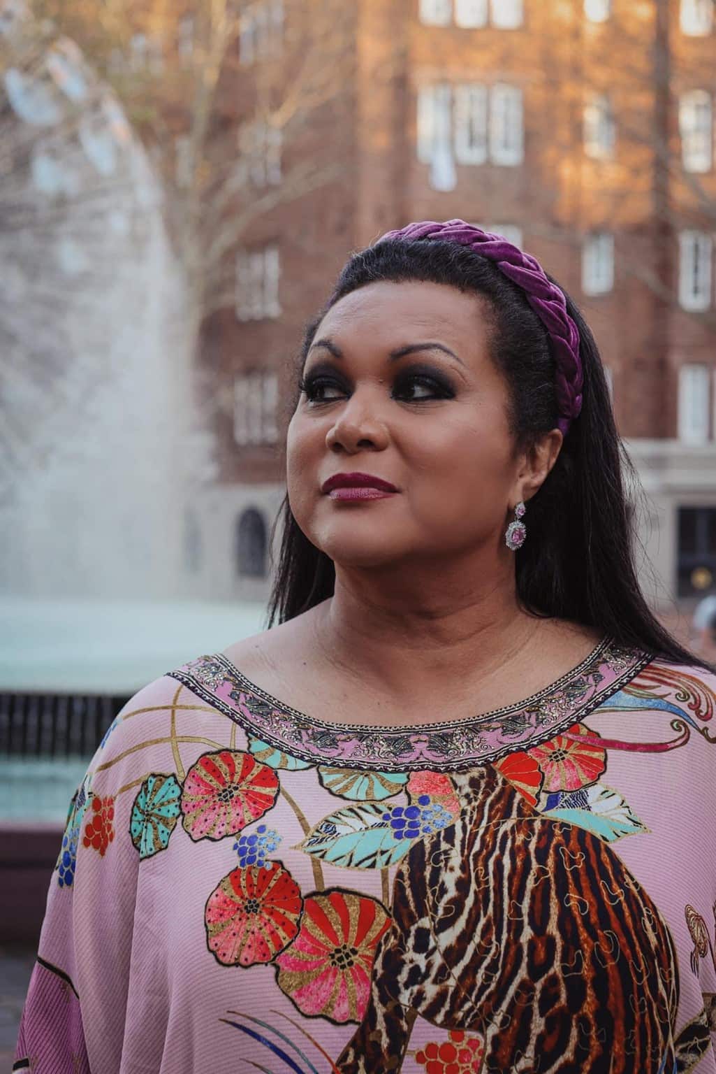 A woman wearing a kaftan and a headband looking off to the left
