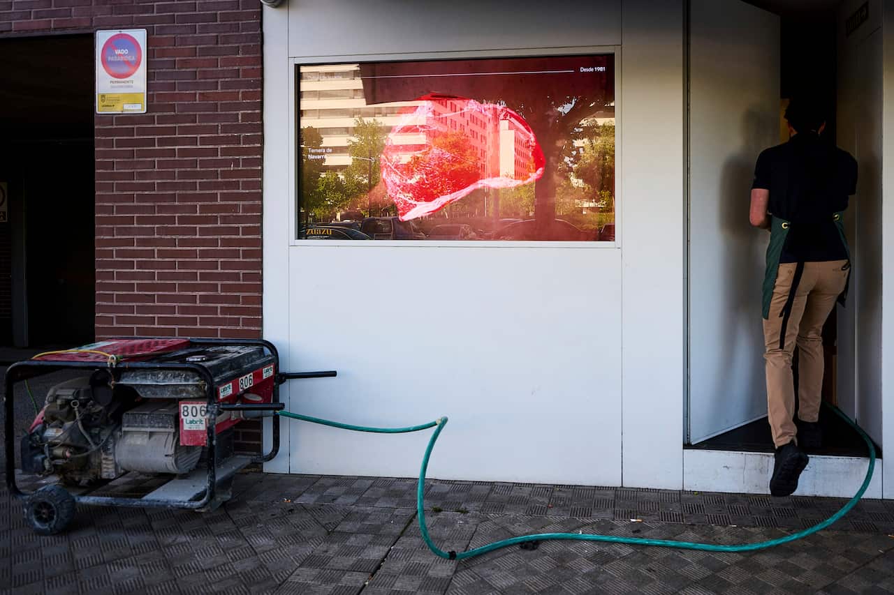 A person is next to a generator outside a meat shop.