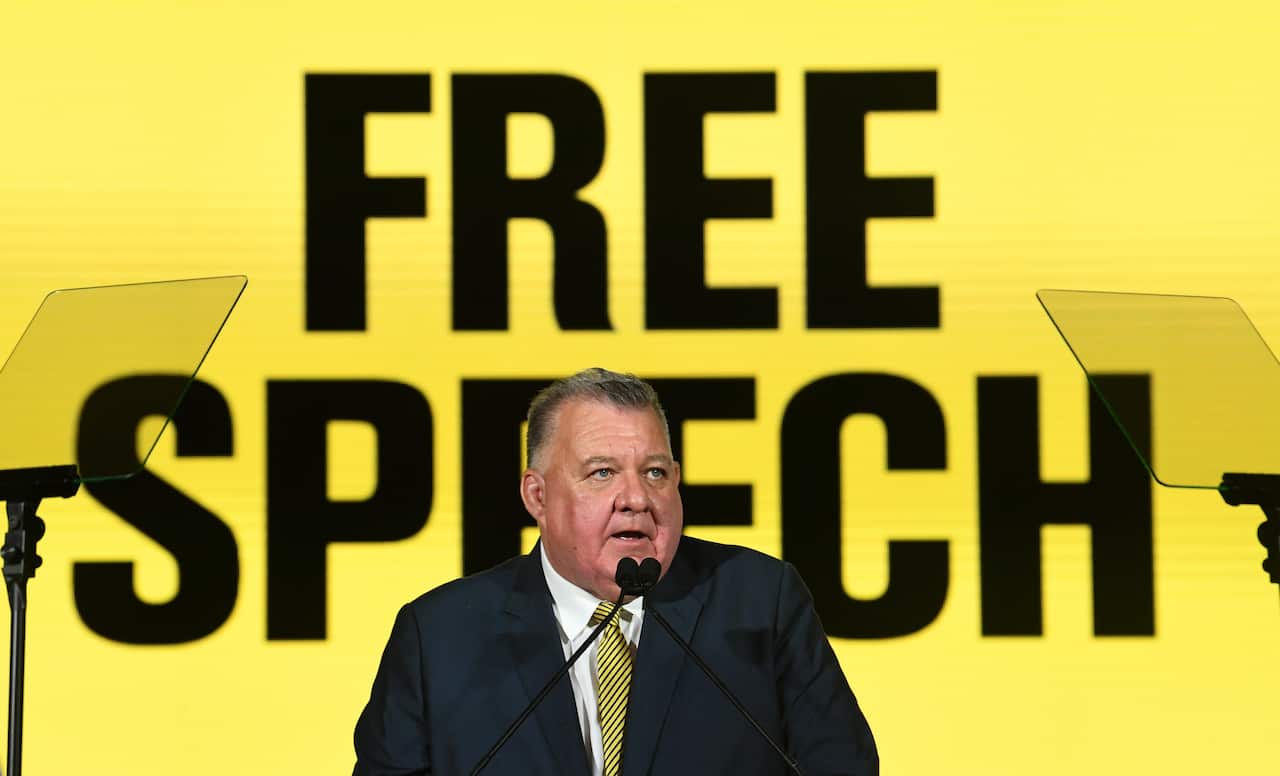 Craig Kelly from UAP standing in front of a 'Free Speech' logo