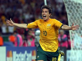Harry Kewell, wearing gold shirt and green shorts, runs in celebration