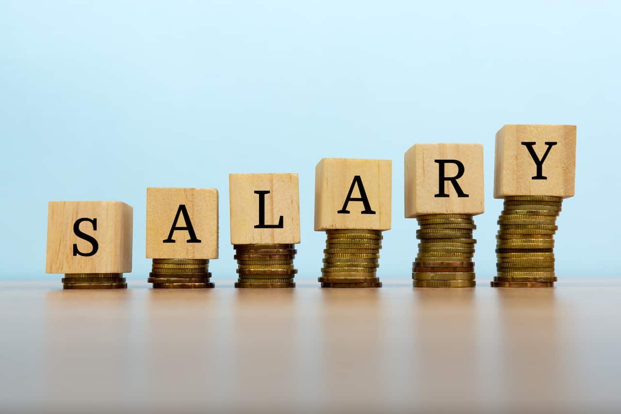 Salary text written on wooden block with stacked coins