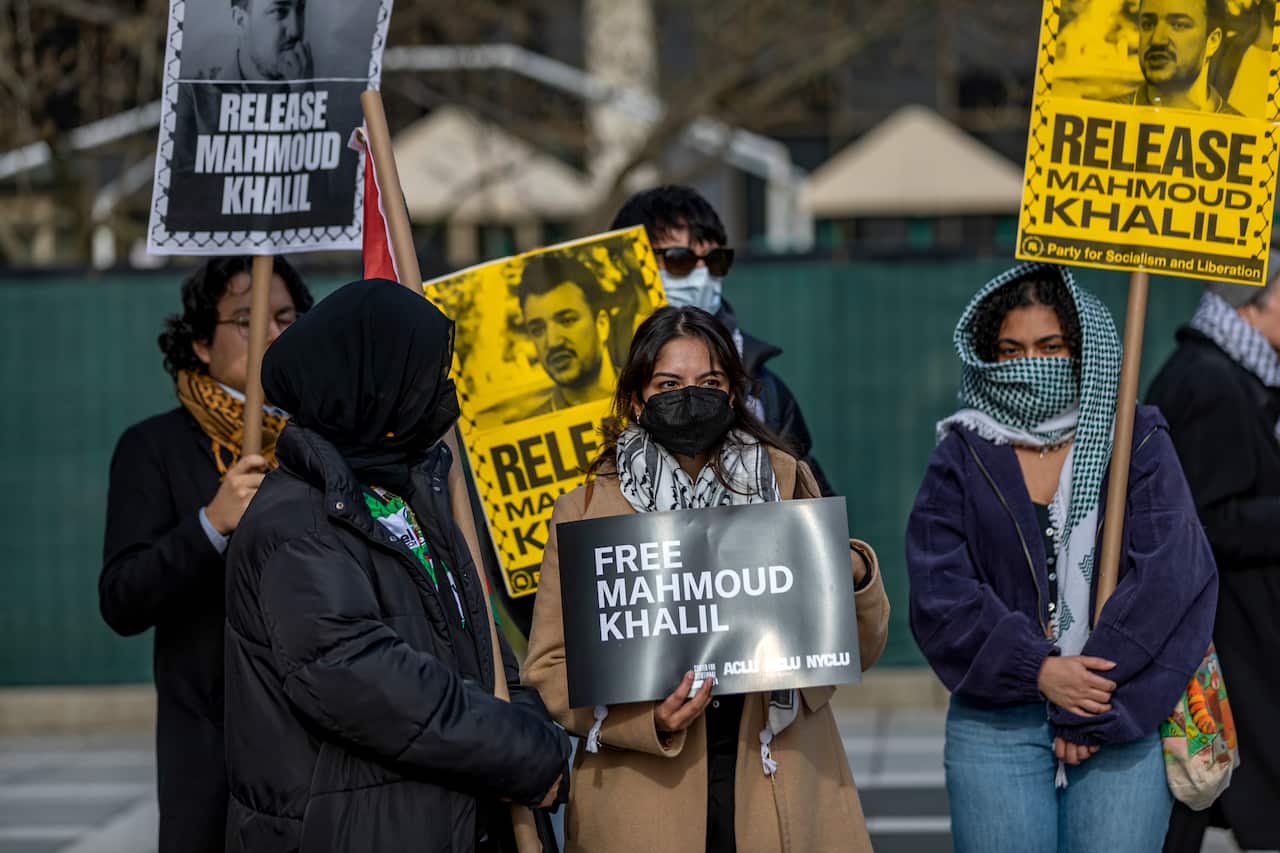 Several people are seen holding signs during a rally. 