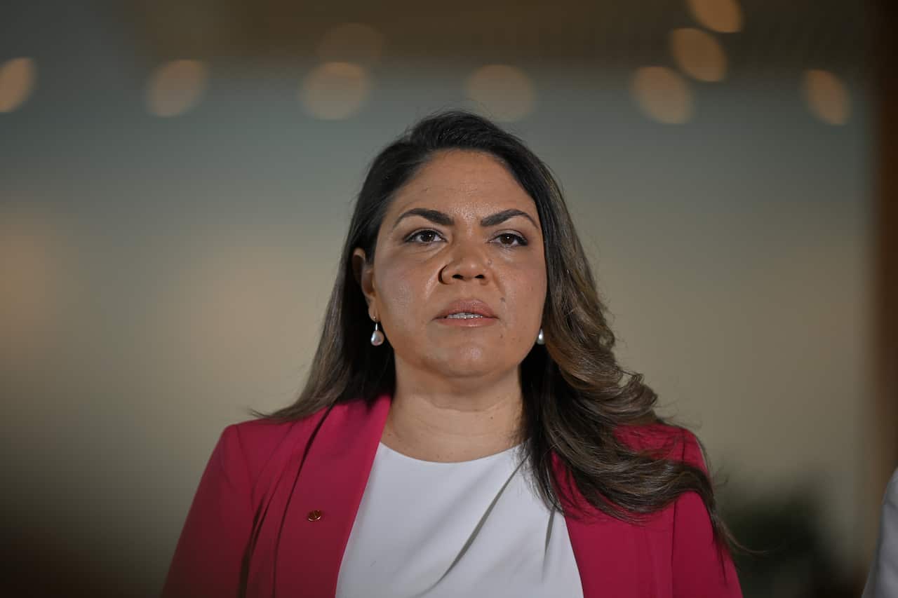 A woman in a white shirt and pink blazer.
