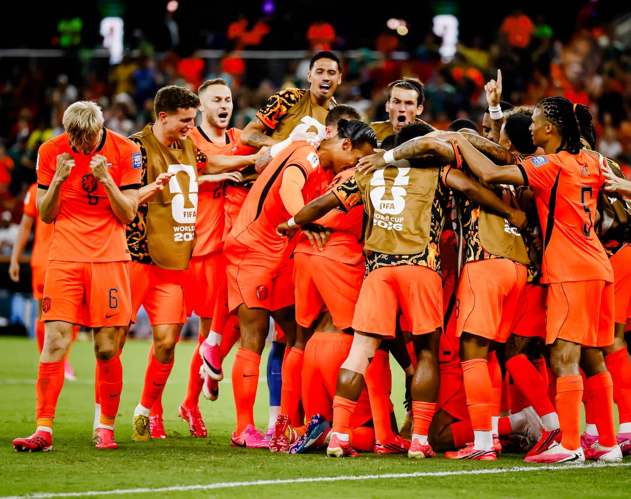 The Netherlands football team, dressed in bright orange clothes, celebrate a goal on the pitch.