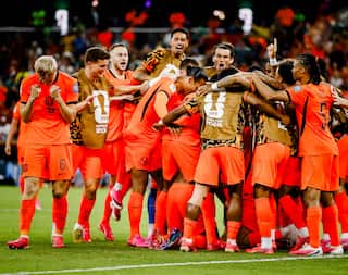 The Netherlands football team, dressed in bright orange clothes, celebrate a goal on the pitch.