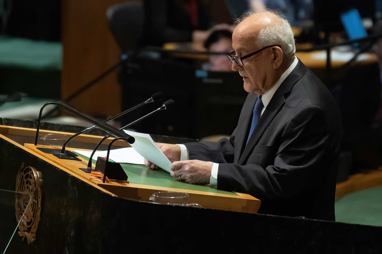 A man holding pieces of paper and speaking at a podium into a microphone.