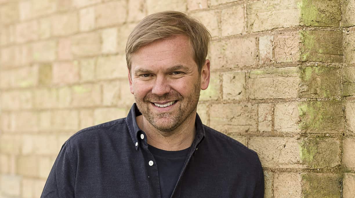 A man standing in front of a brick wall and smiling