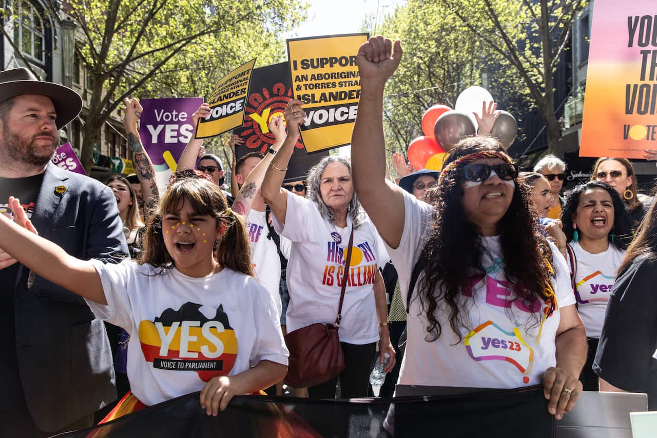 People wearing 'Yes' tshirts and holding sigs supporting the Voice to Parliament march on streets