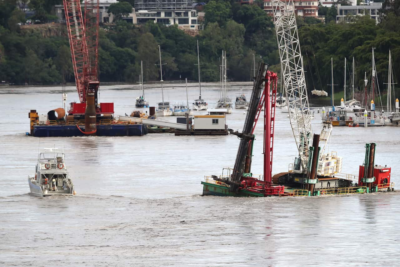 A special boar tries to secure a floating crane as it comes loose near Eagle Street Pier, in Brisbane.