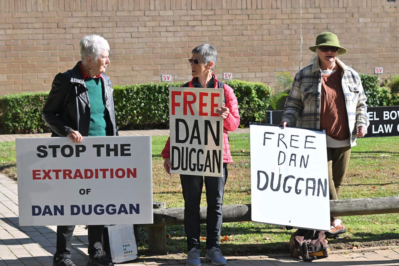 Three people holding placards with text reading 'Free Dan Duggan'