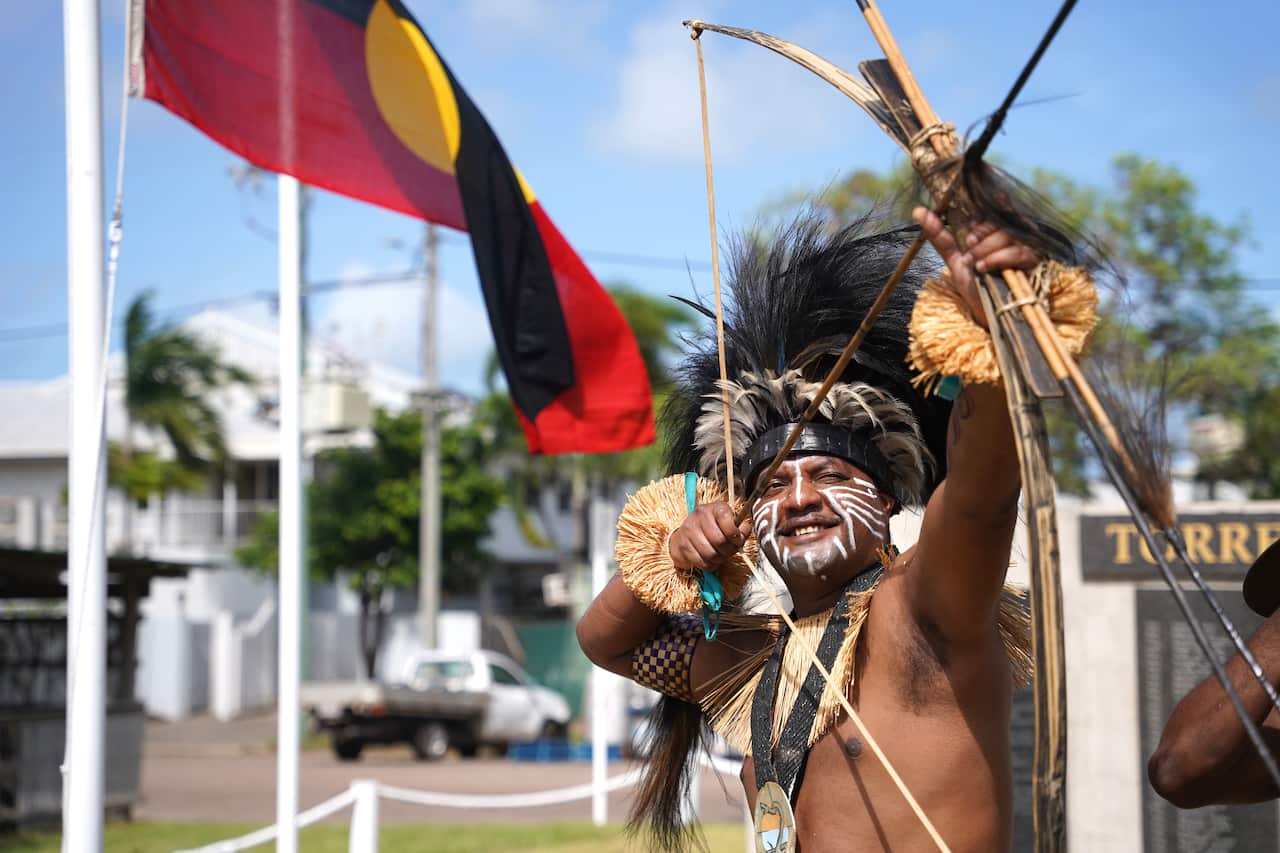 Un hombre que lleva un tocado tradicional dispara una flecha.