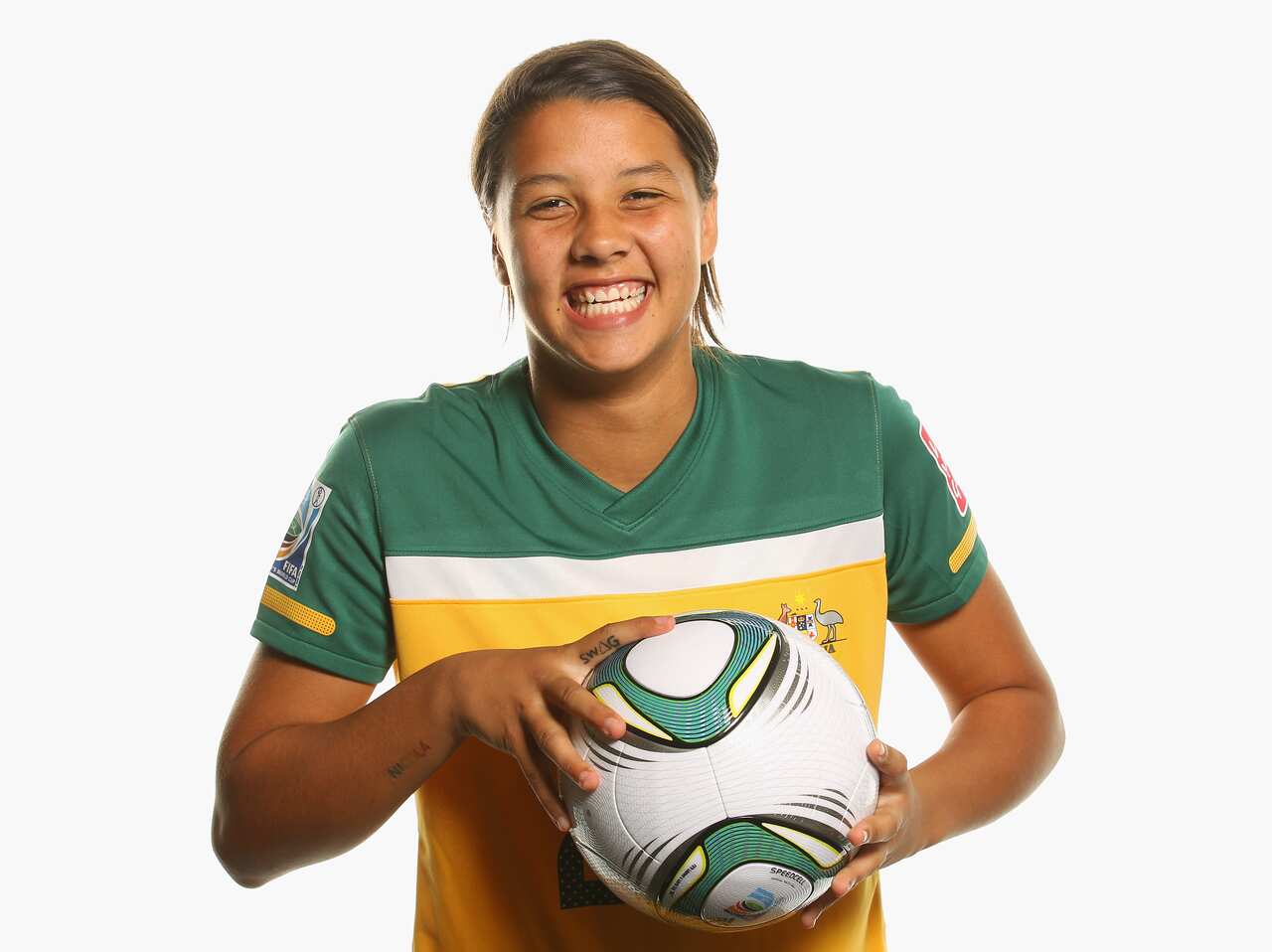 Sam Kerr smiling and holding a soccer ball.
