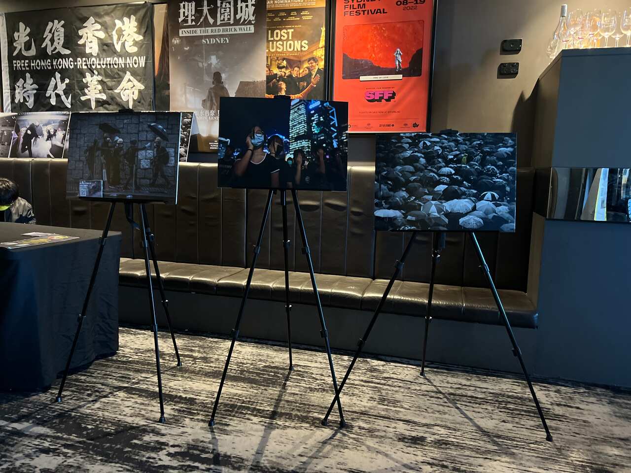 Promotional materials and photographs on stands showing scenes from Hong Kong's protest movement.