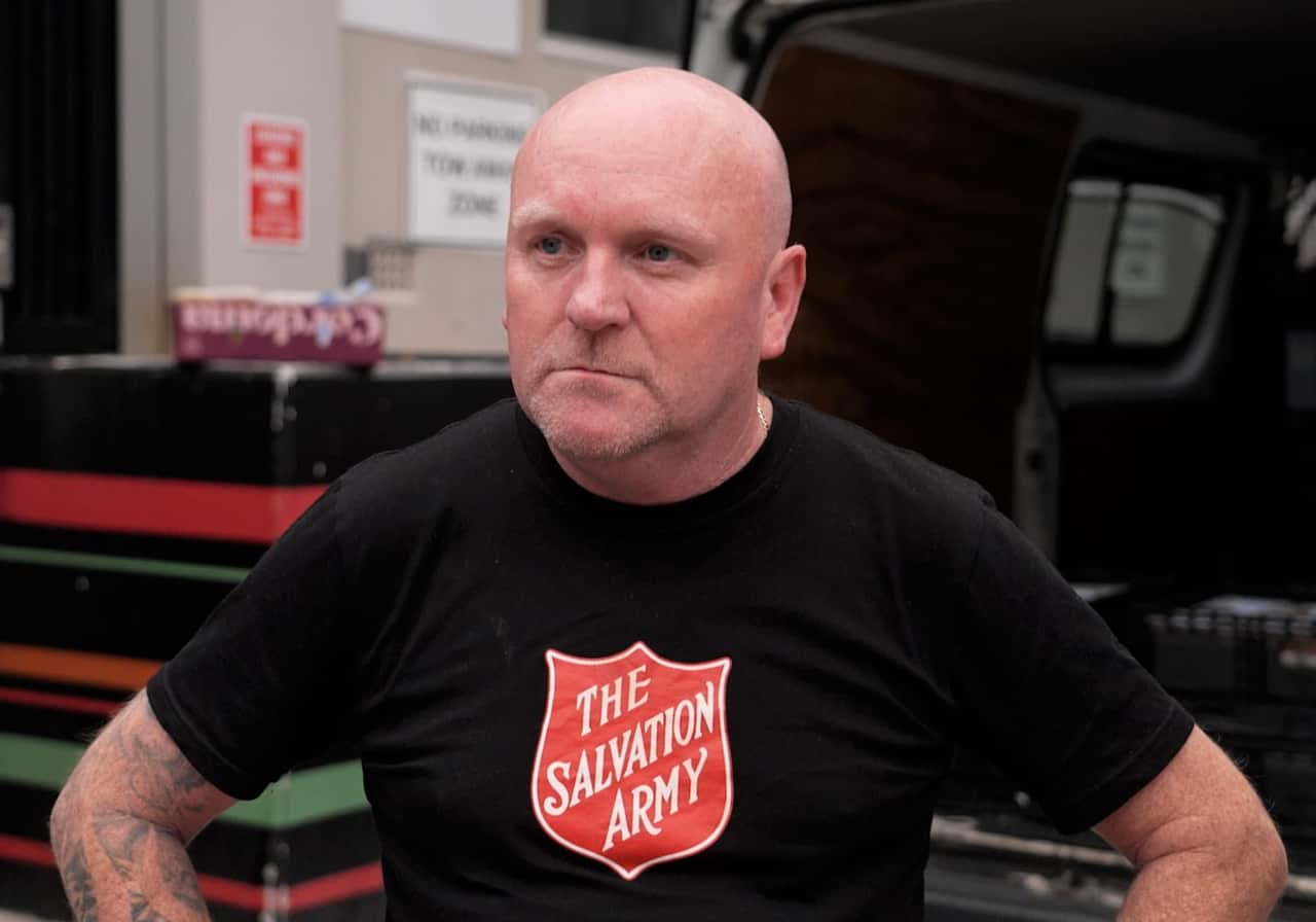 A man wearing a black t-shirt with a Slavation Army logo.
