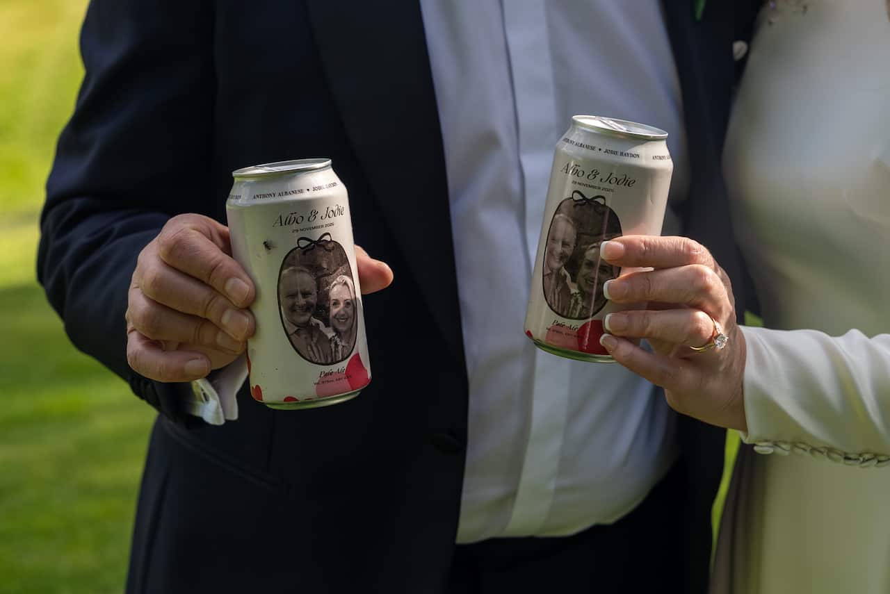 Anthony Albanese and Jodie Haydon holding up a special beer can with their picture on it.