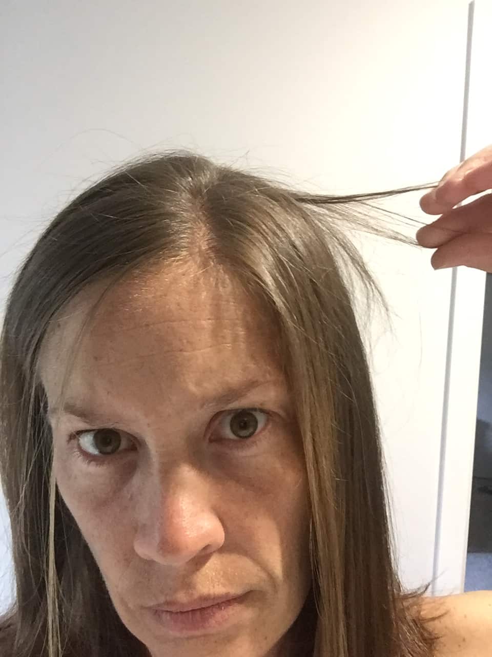 A woman showing her broken hair with a serious expression on her face.