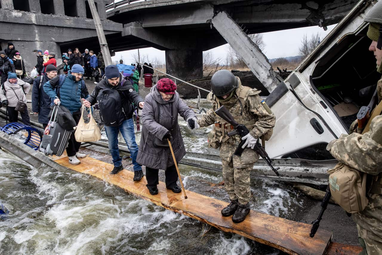 Residents of Irpin are seen fleeing via a destroyed bridge.