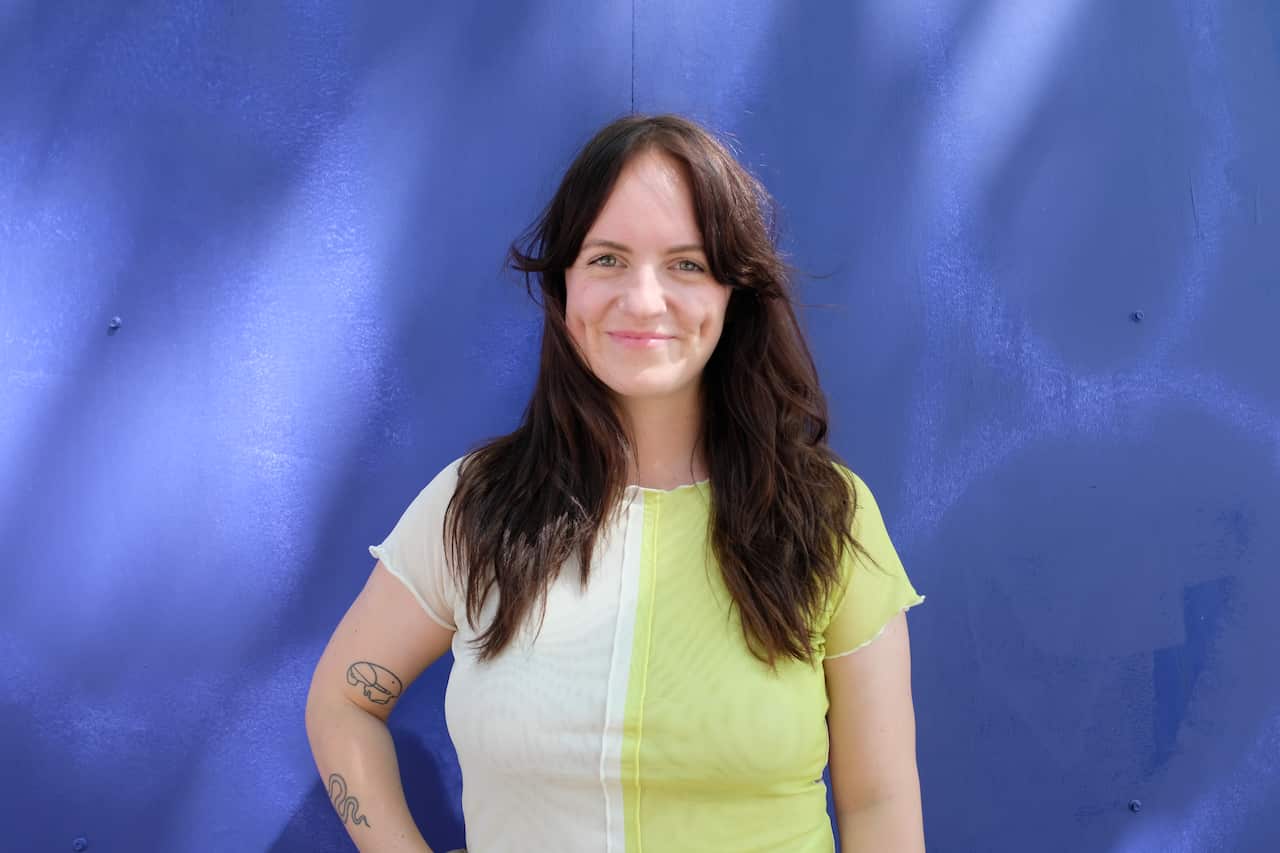 Woman standing in front of a blue wall. 
