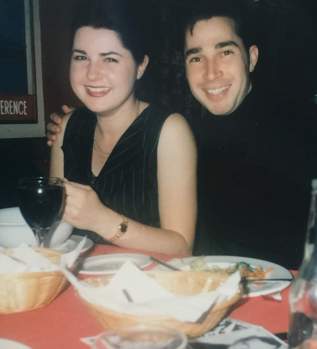 Sherrie and Sasha laughing at dinner. Sacha has his arm around Sherrie's shoulders.