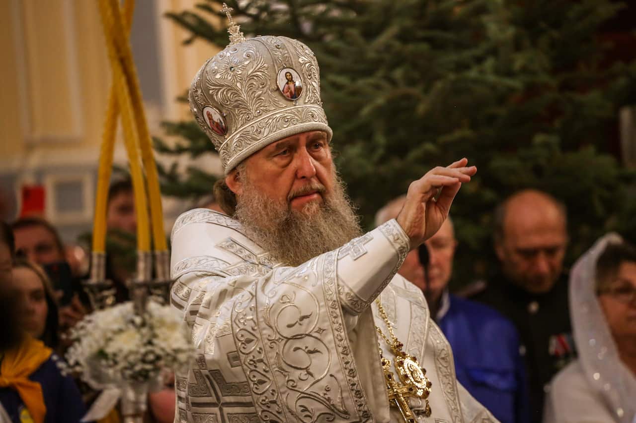 A clergyman in a white ceremonial robe leads a mass during the Orthodox Christmas celebrations