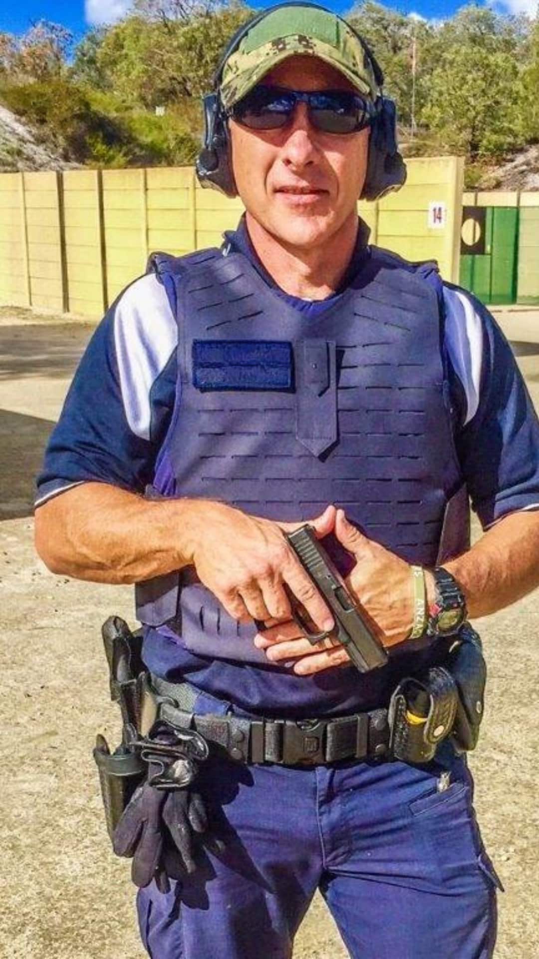 Man wearing an Australian Federal Police uniform holding a gun.