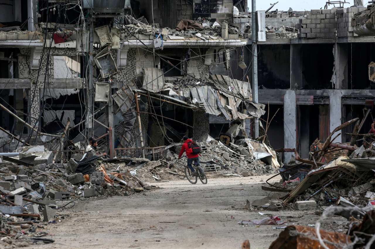 A person rides a bike through the rubble in Gaza