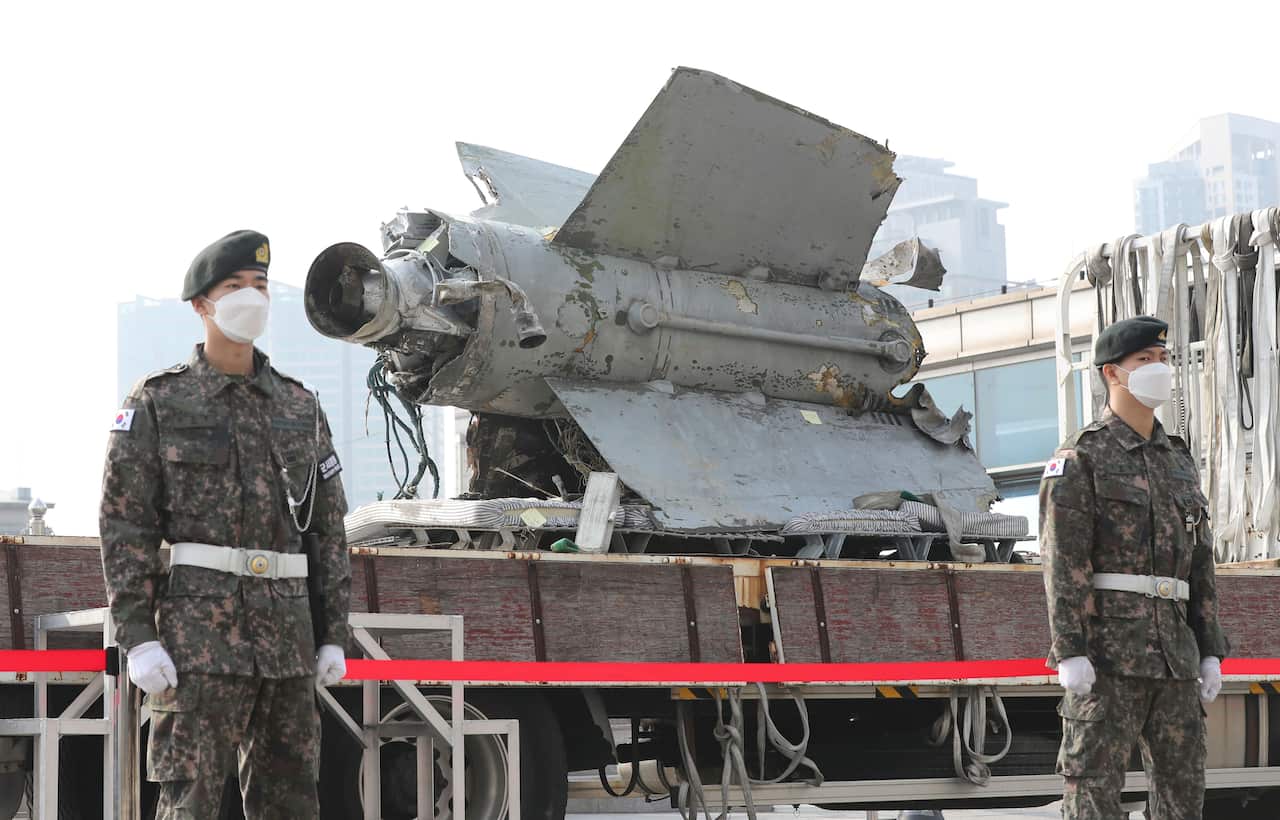 Soldiers standing next to debris from a missile.