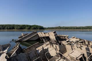 the hulk of a ship next to a river