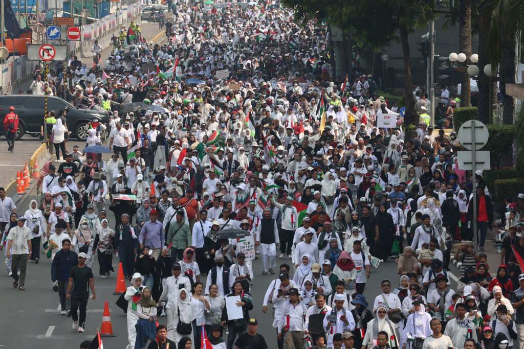 Thousands of pro-Palestinian demonstrators march along a street.