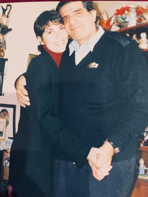 An adult daughter hugs her father, with both of them smiling.