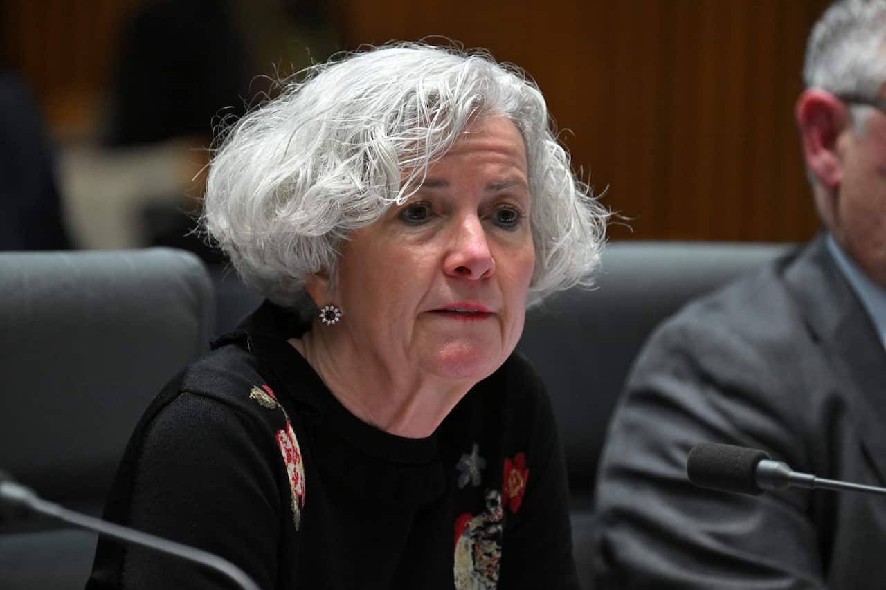 A woman with grey hair sitting at a desk.