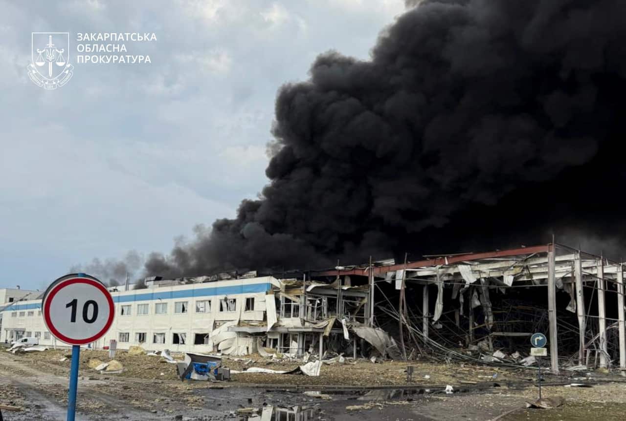 Black smoke billowing from a building that has been badly damaged.