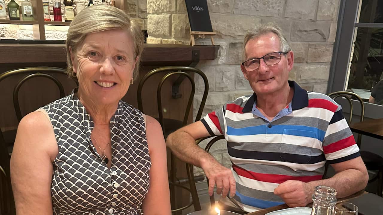 a middle aged couple - woman and man - smile sitting in a restaurant together